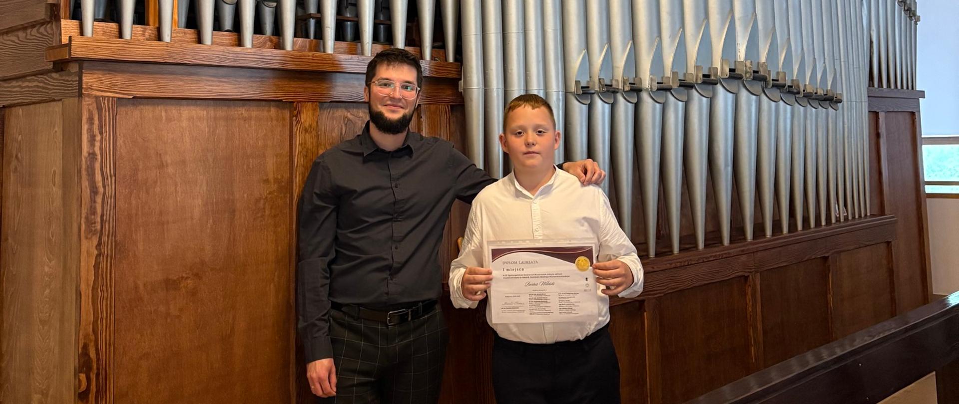 Uczeń z nauczycielem na tle organów.