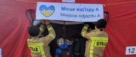 Strażacy pomogli w przygotowaniu tymczasowego punktu przyjęcia obywateli Ukrainy Montują napis na namiocie