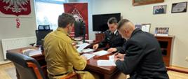 Fotografia przedstawia druhów OSP oraz Komendanta Powiatowego PSP podpisujących w gabinecie Komendanta umowy dotyczące uzyskania uprawnień kategorii C.