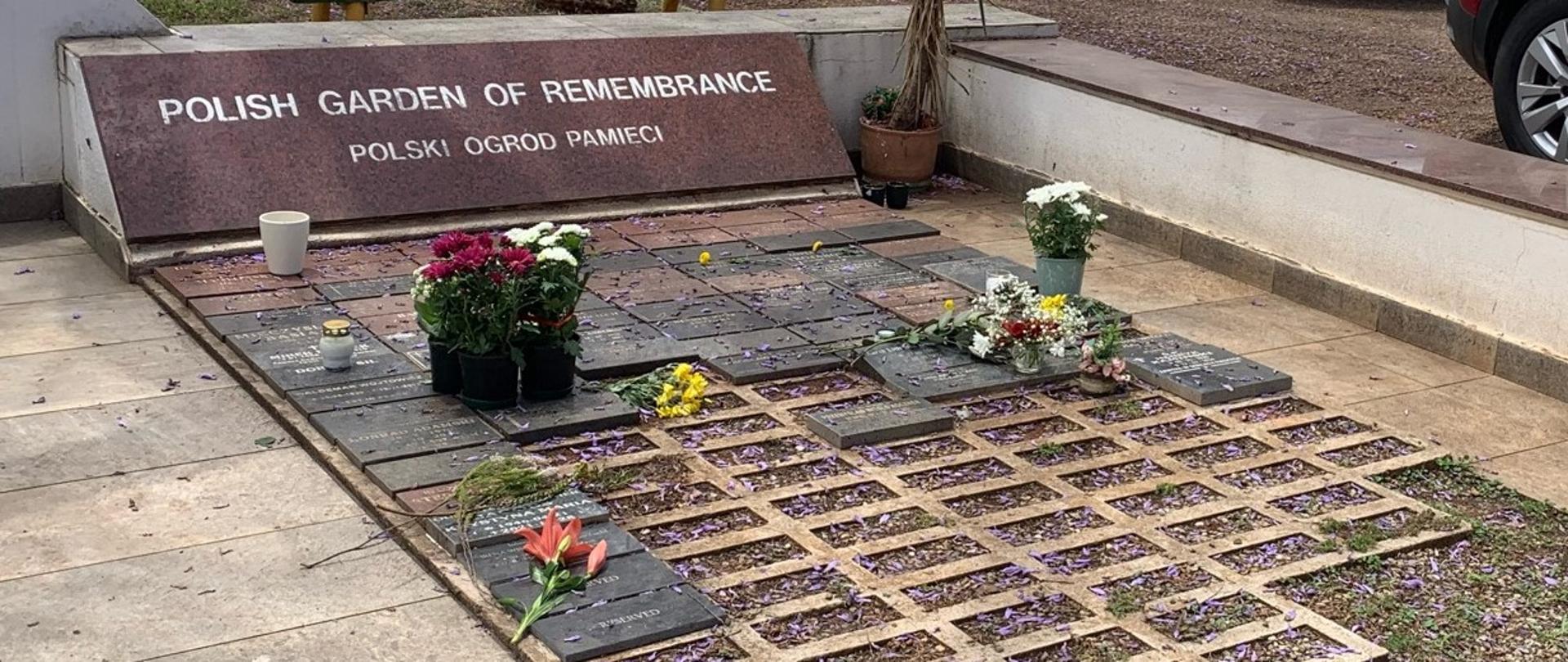 Pomnik - Polish Garden of Remembrance; tablice pamiątkowe; na tablicach leżą kwiaty i stoją doniczki z kwiatami