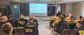 Zdjęcie przedstawia strażaków siedzących w świetlicy jednostki podczas szkolenia z kierowana działaniem ratowniczym. 