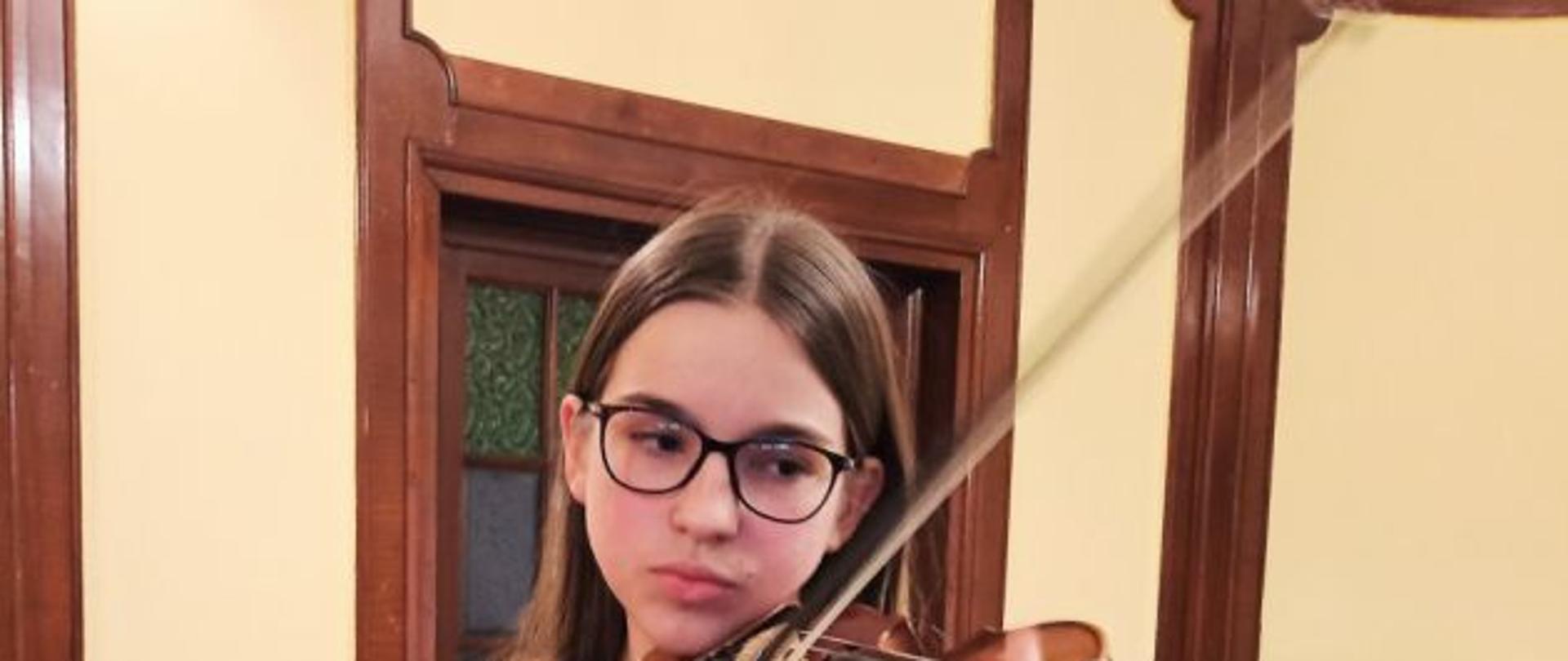 Zdjęcie kolorowe przedstawiające uczennicę klasy skrzypiec ze skrzypcami.