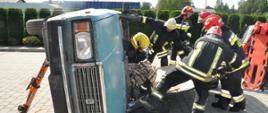 Strażacy ćwiczący uwalnianie osoby znajdującej się przewróconym pojeździe