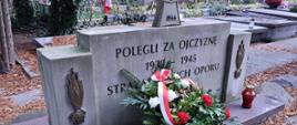 Kwiaty złoże na grobie zasłużonych strażaków. 