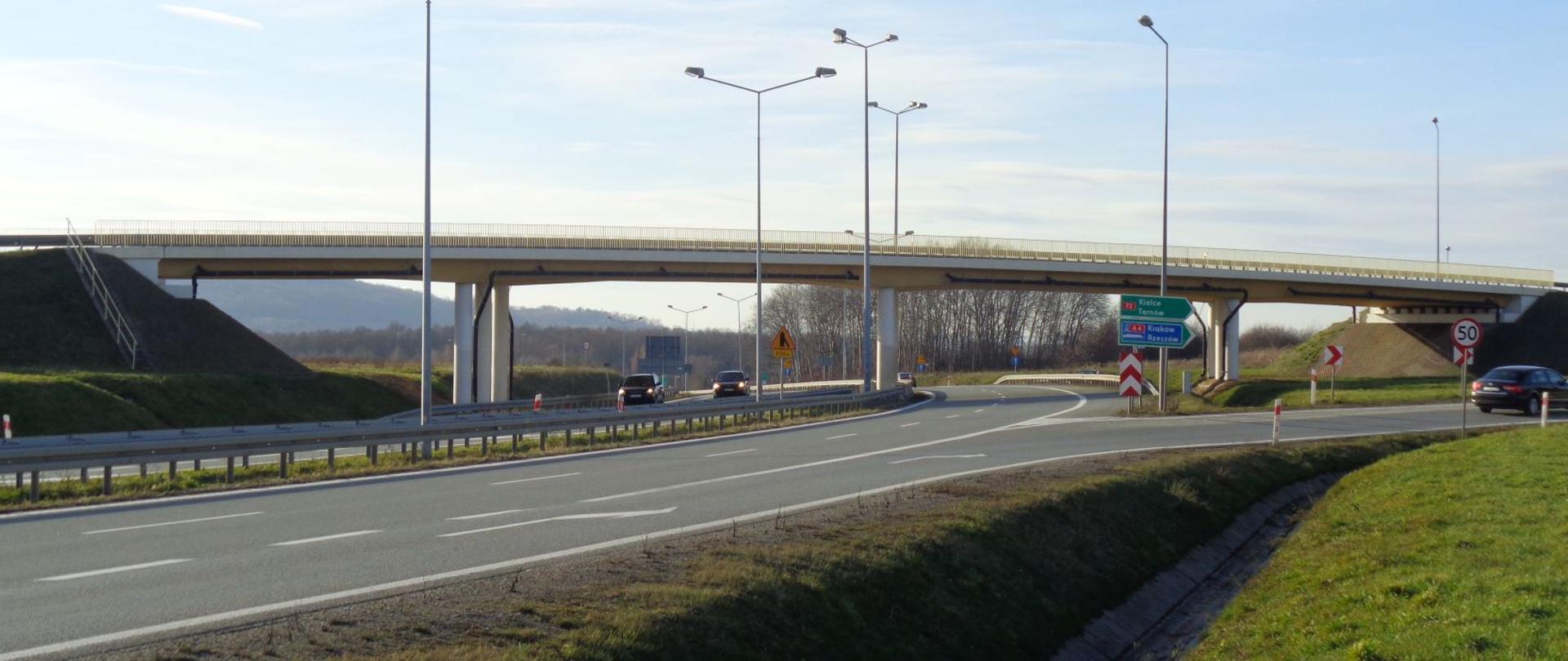 węzeł drogowy, nad drogą wiadukt, w tle drzewa i wzgórza