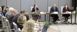 Pierwsze posiedzenie Rady Wykonawczej ds. wdrażania Krajowej Polityki Miejskiej 2030, uczestnicy obrad siedzą przy stole, w centrum kadru minister funduszy i polityki regionalnej Grzegorz Puda 