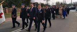 Zdjęcie przedstawia strażaków, druhów OSP i parlamentarzystów podczas obchodów Dnia Strażaka Gminy Golina, którzy maszerują