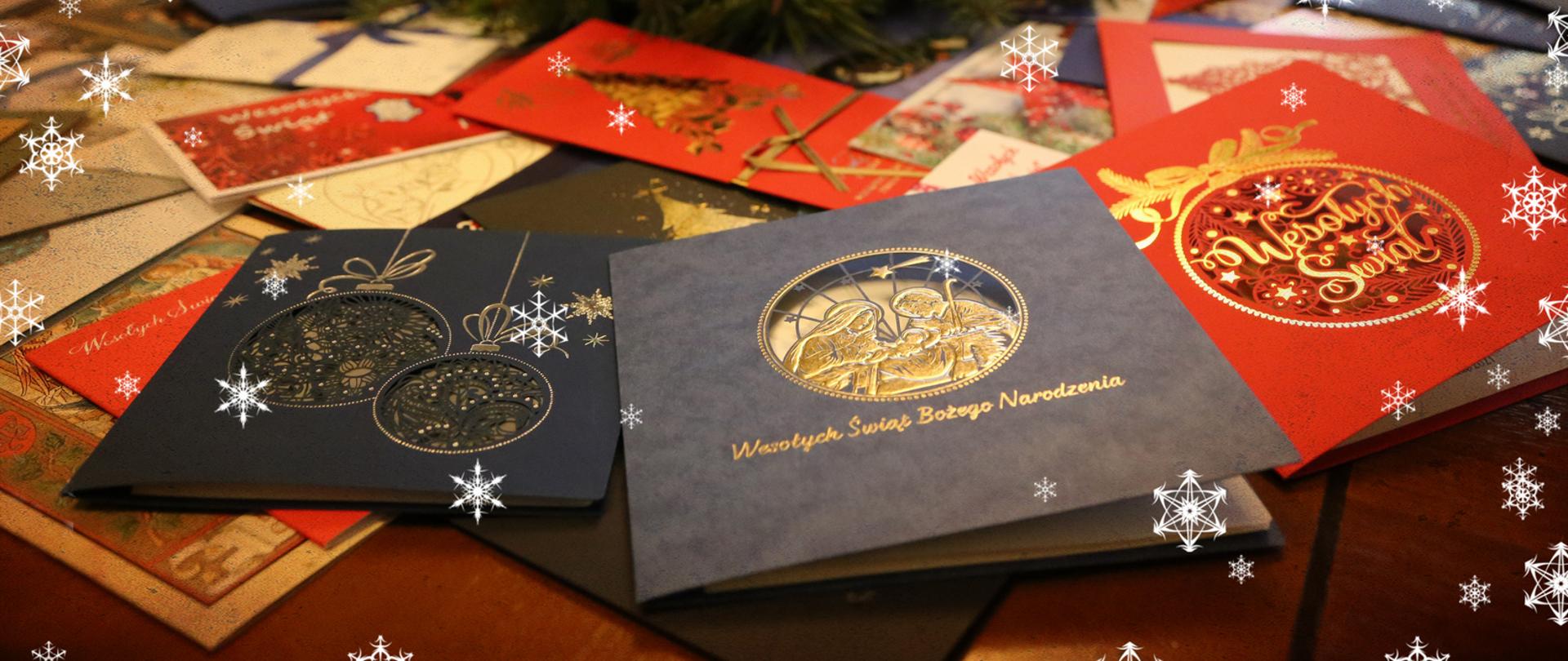 Leżące na blacie biurka kartki świąteczne otrzymane przez Komendanta Centralnej Szkoły PSP. w tle świąteczny stroik. Na fotografii naniesione śnieżynki