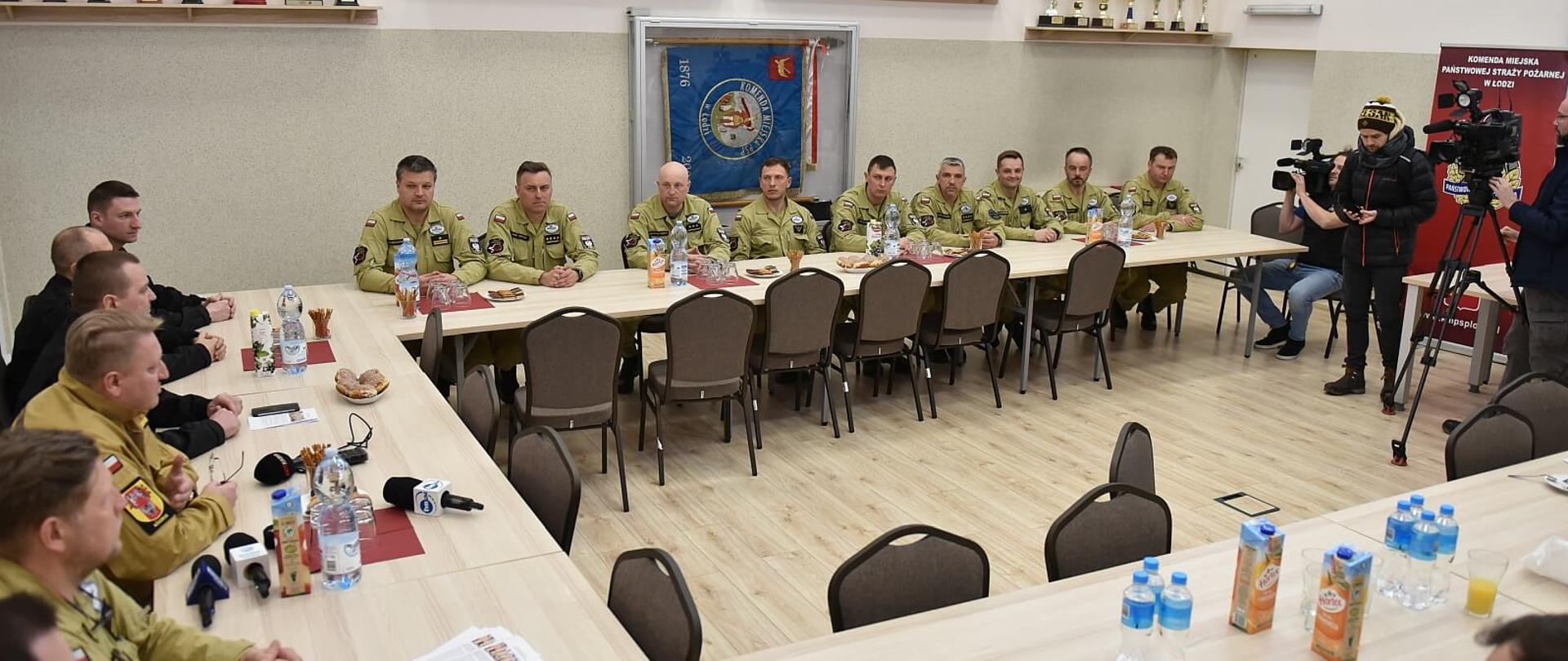 strażacy członkowie specjalistycznej grupy poszukiwawczo-ratowniczej w czasie spotkania, siedzą przy stołach w sali konferencyjnej