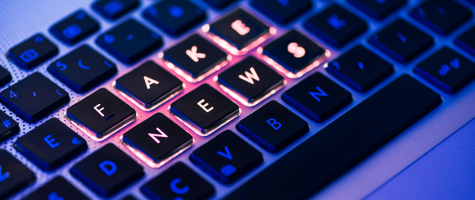Klawiatura komputera. Na środku podświetlone litery układające się w słowa fake news.