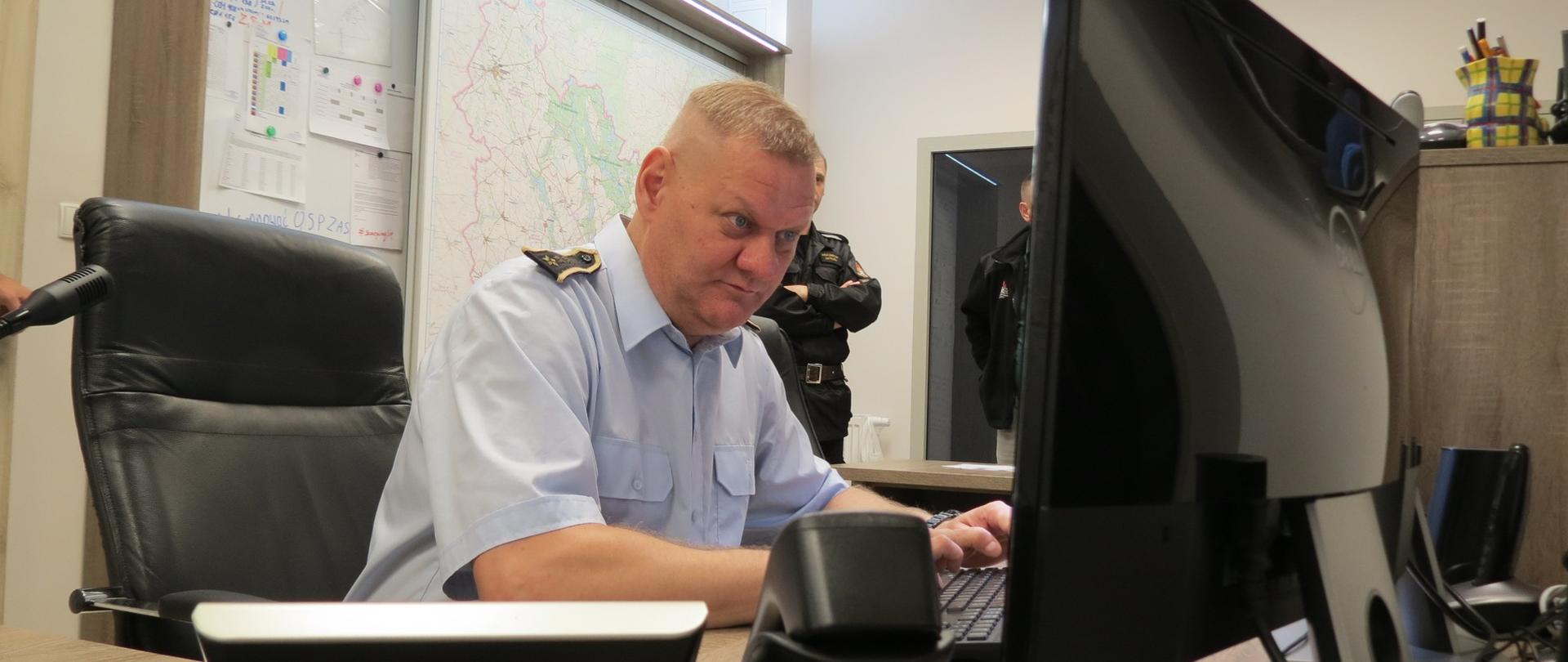Zdjęcie przedstawia asp. sztab. Jacka Wrzesińskiego podczas pracy w Stanowisku Kierowania Komendanta Powiatowego