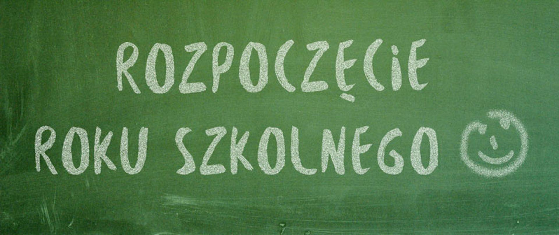 Klasyczna, zielona tablica szkolna z napisem wykonanym kredą "Rozpoczęcie roku szkolnego"