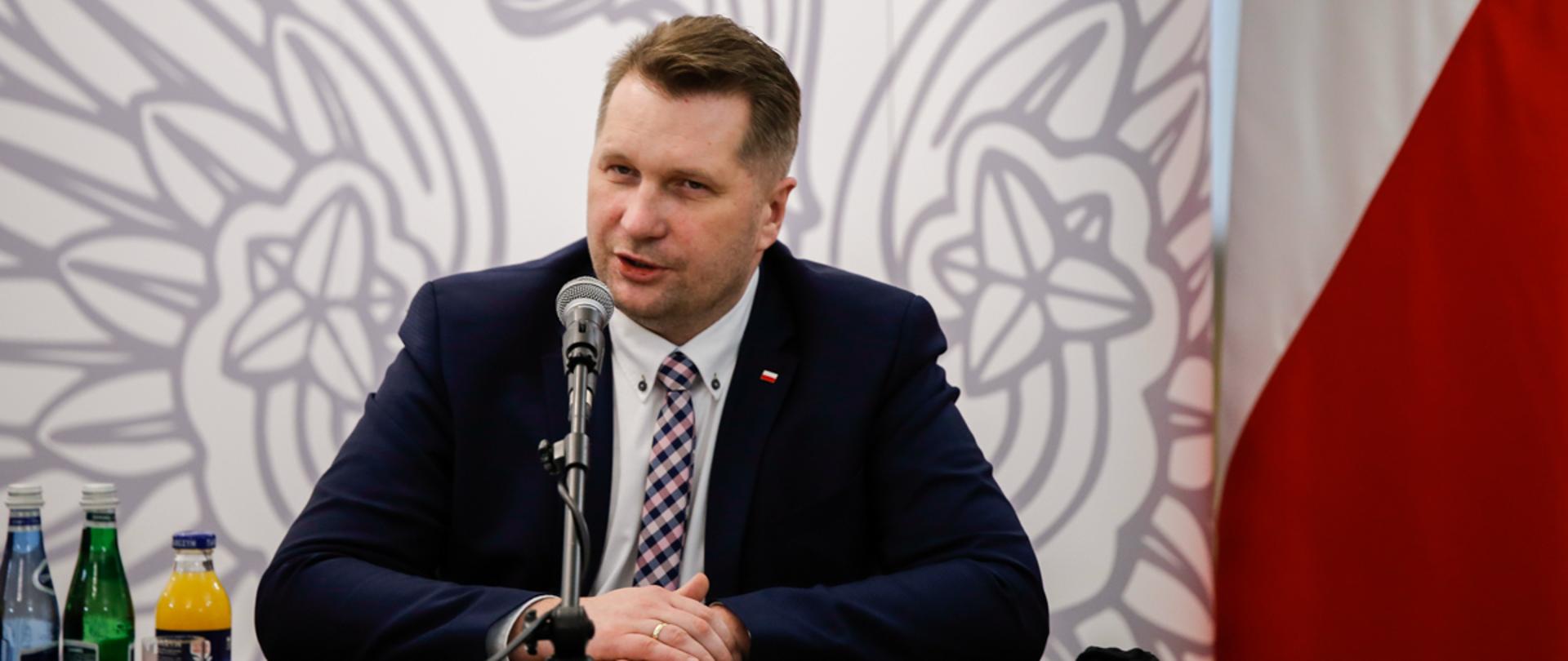 Minister Edukacji i Nauki zabiera głos siedząc przy stole