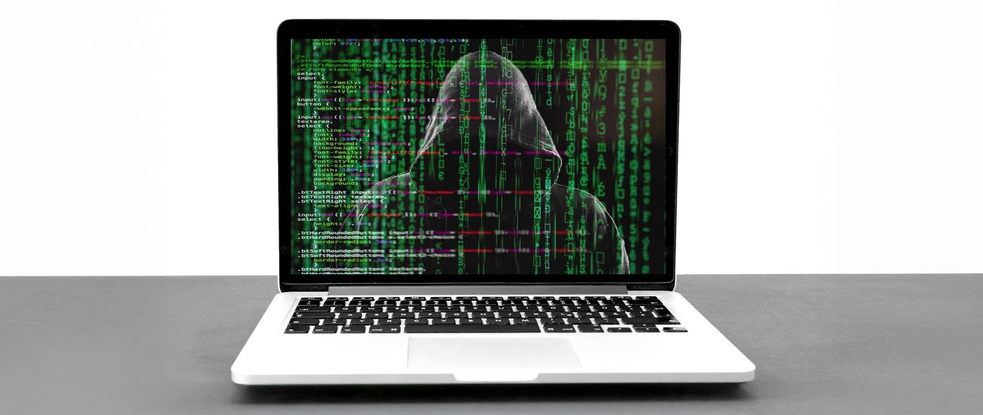 Laptop, w tle zamaskowany haker