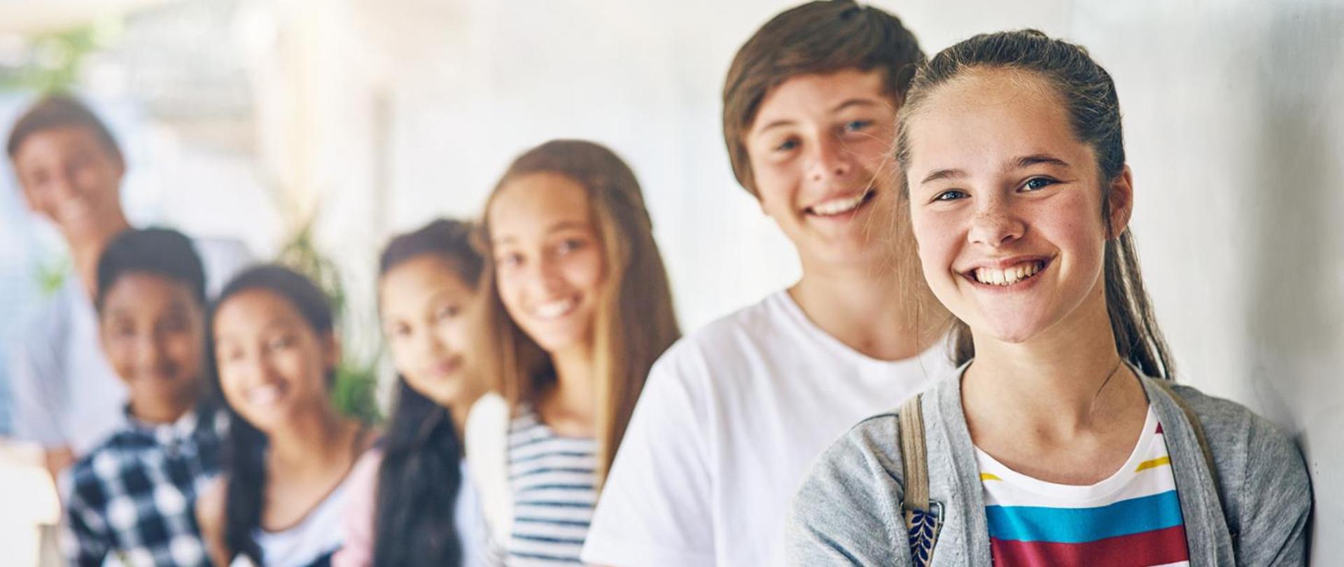 Teenager, friends and portrait on school campus or learning development, education or scholarship. Girls, boys and face in building hallway with books for student studying or together, group or smile