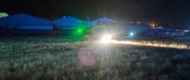 Na zdjęciu widoczny helikopter Lotniczego Pogotowia Ratunkowego na łące. Z przodu śmigłowca widoczne silne światło reflektora, a na ogonie maszyny światło zielone.