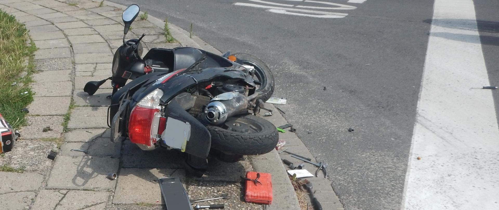 Zdjęcie przedstawia motocykl, który brał udział w zdarzeniu. Motocykl znajduje się na chodniku.