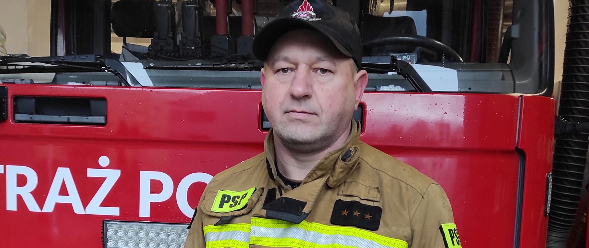 Na zdjęciu na tle samochodu strażackiego aspirant sztabowy Byczko Jarosław