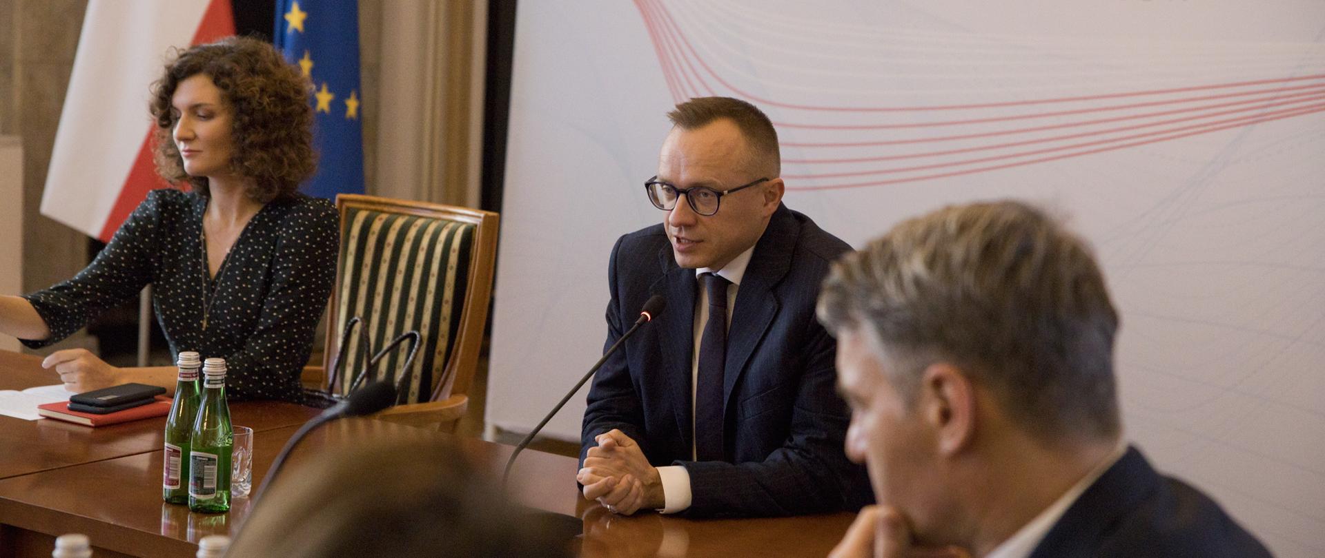 Minister Soboń podczas prezentacji na tle baneru MF