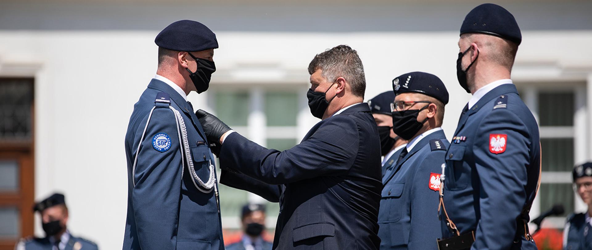 Wiceminister Maciej Wąsik w towarzystwie komendanta SOP odznacza medalem za długoletnią służbę jednego z funkcjonariuszy SOP.