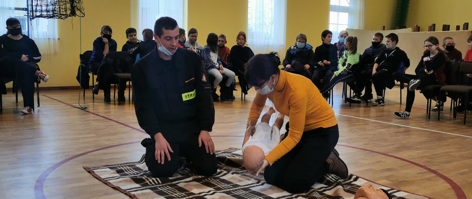 Strażak wydaje instrukcje KPP przy dziecku.