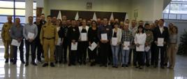 Grupowe zdjęcie uczestników szkolenia (32 osoby) w towarzystwie Komendanta Centralnej Szkoły PSP, dwóch funkcjonariuszy CS PSP oraz kobiety