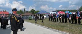 na zdjęciu widzimu rozpoczęcie uroczystości i przyjmowanie meldunku, strażaków w mundurach wyjściowych, poczet sztandarowy, w tle namioty, drzewa