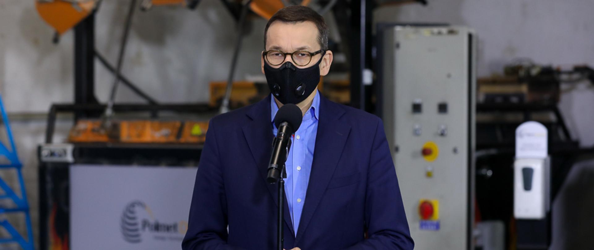 Premier Mateusz Morawiecki stoi podczas konferencji prasowej.