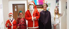 Grupa pięciu uczniów przebrana w stroje Św. Mikołaja, elfa, anioła i diabła stoi w budynku.