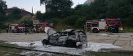 Samochód osobowy uległ spaleniu, na miejscu strażacy zabezpieczają teren zdarzenia.