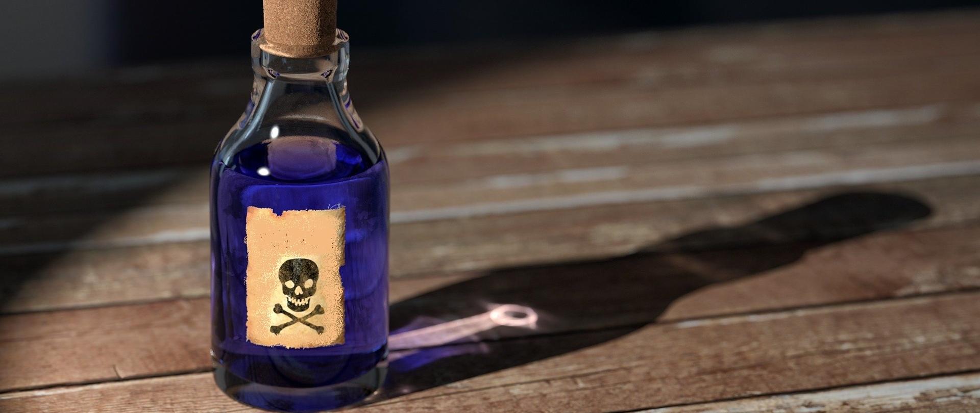 fiolka z fioletowym płynem oznaczona jak trucizna na drewnianym blacie.
