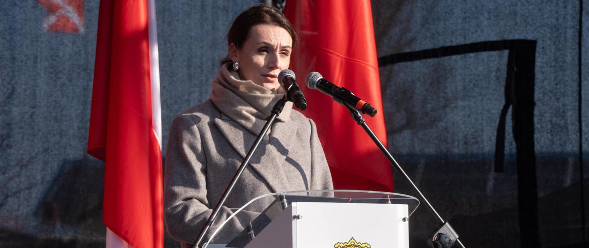 kobieta stoi przy mównicy i czyta przemówienie