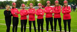 Zawodniczki kobiecej drużyny Centralnej Szkoły PSP (osiem kobiet) w strojach sportowych oraz kasku na głowie na murawie stadionu pozują do pamiątkowego zdjęcia