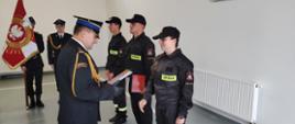 Zdjęcie przedstawia Komendanta Powiatowego PSP w Lwówku Śląskim w trakcie wręczania aktu mianowania nowo przyjętym strażakom. 