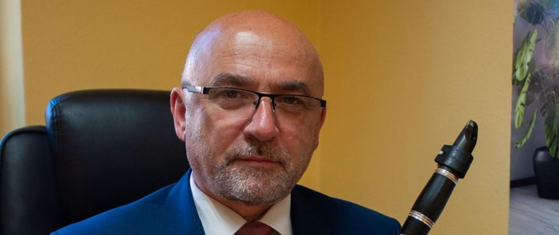 Zdjęcie przedstawia dyrektora PSM w K.-Koźlu, siedzącego za biurkiem i trzymającego klarnet