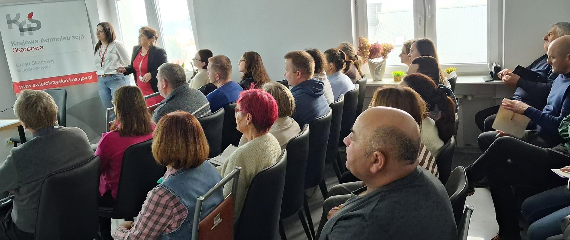 W sali siedzi grupa osób i słucha wykładu o Krajowym Systemie e-Faktur