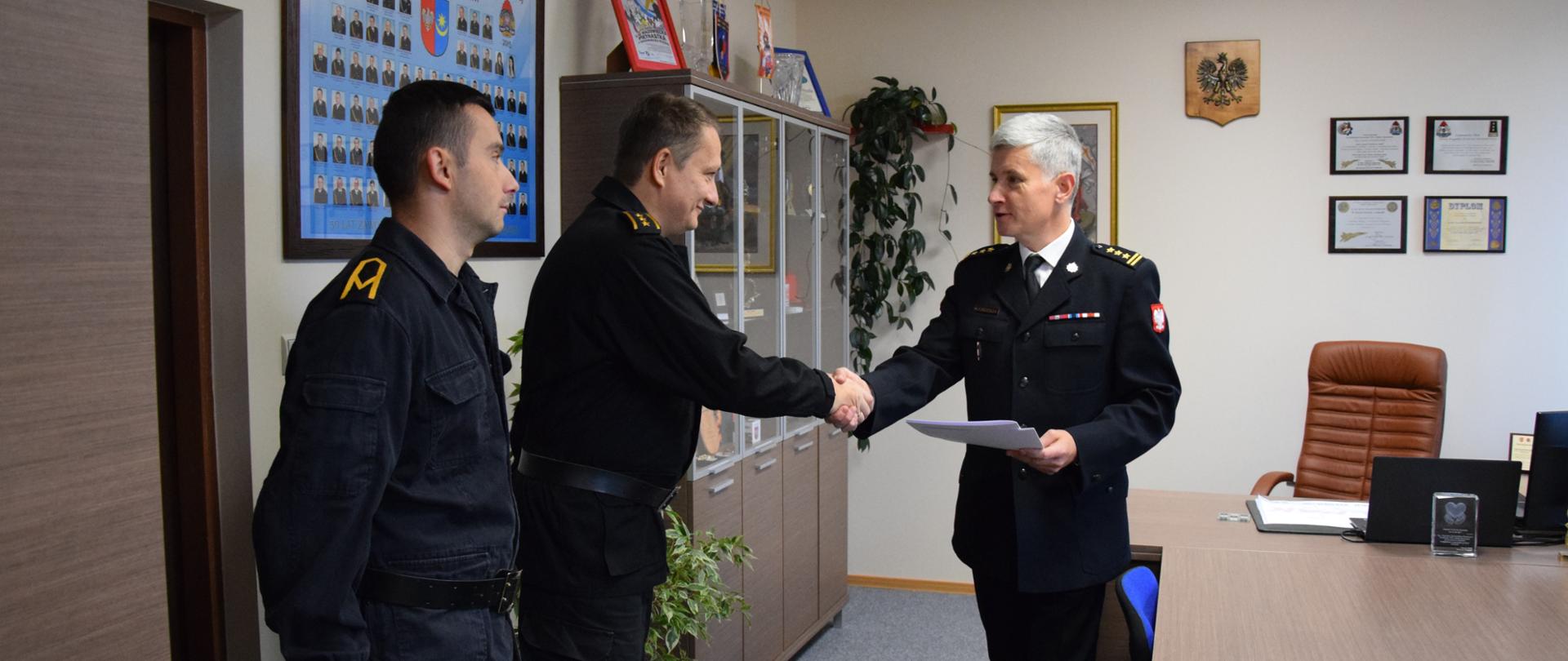 Komendant Powiatowy PSP gratuluje i wręcza wyciąg z rozkazu ws. przyznania nagrody pieniężnej asp. sztab. Andrzejowi Nowakowi