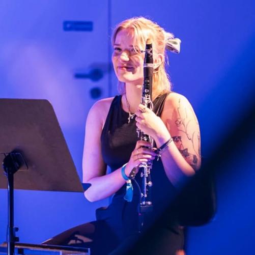 Kobieta siedzi na krześle i trzyma klarnet.