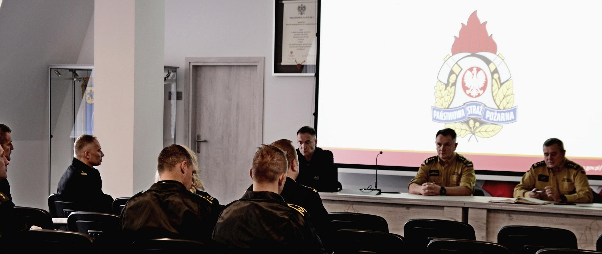 Kierownictwo Komendy Wojewódzkiej Państwowej Straży Pożarnej w Gdańsku, przedstawiciel Komendy Główne Państwowej Straży Pożarnej omawiają propozycję zmian w aktach prawnych przed funkcjonariuszami z komend wojewódzkich Państwowej Straży Pożarnej w Szczecinie oraz Olsztynie.
