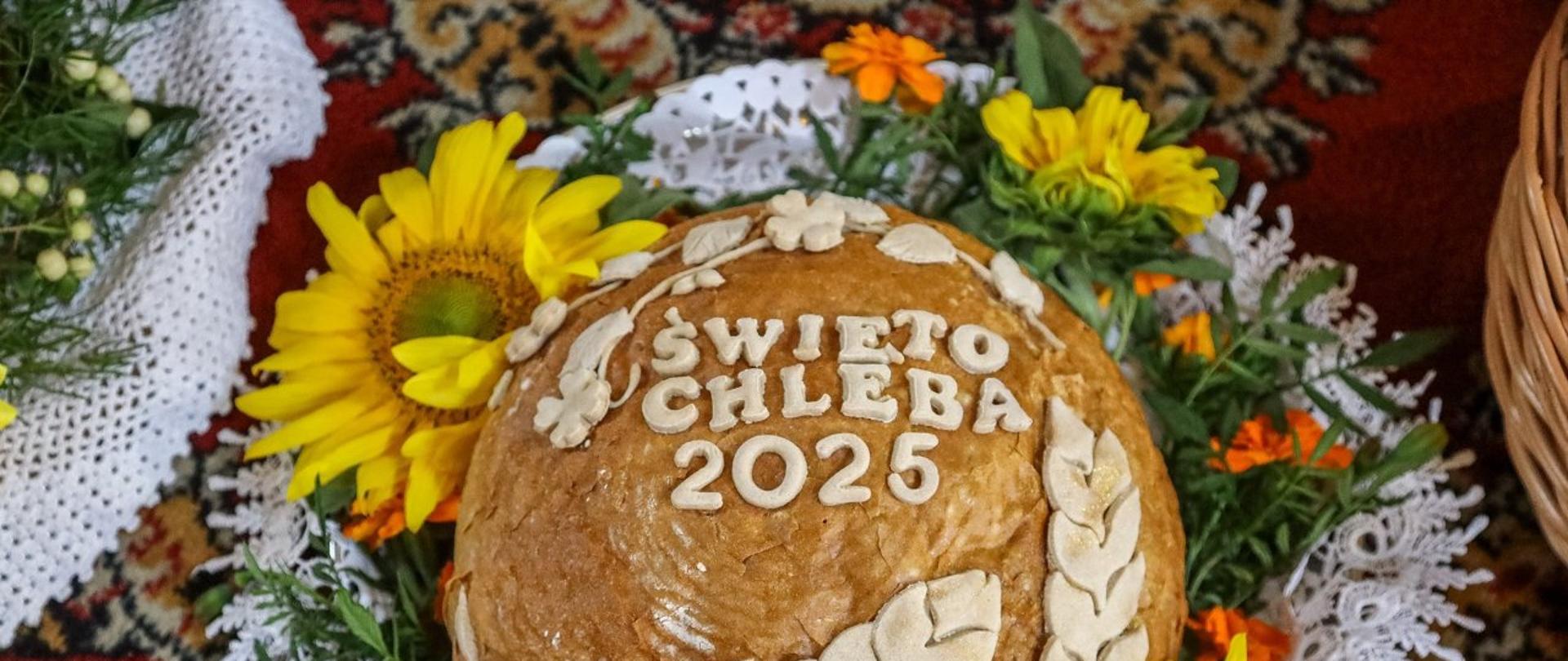 Zdjęcie okrągłego bochenka chleba , ozdobiony jest kwiatami. 