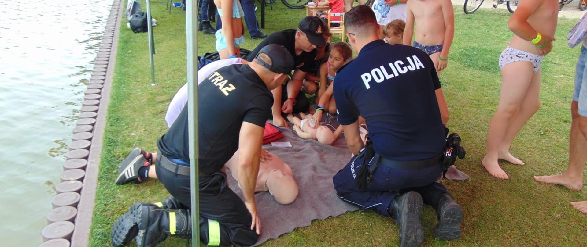 Strażacy i policjanci uczą pierwszej pomocy.