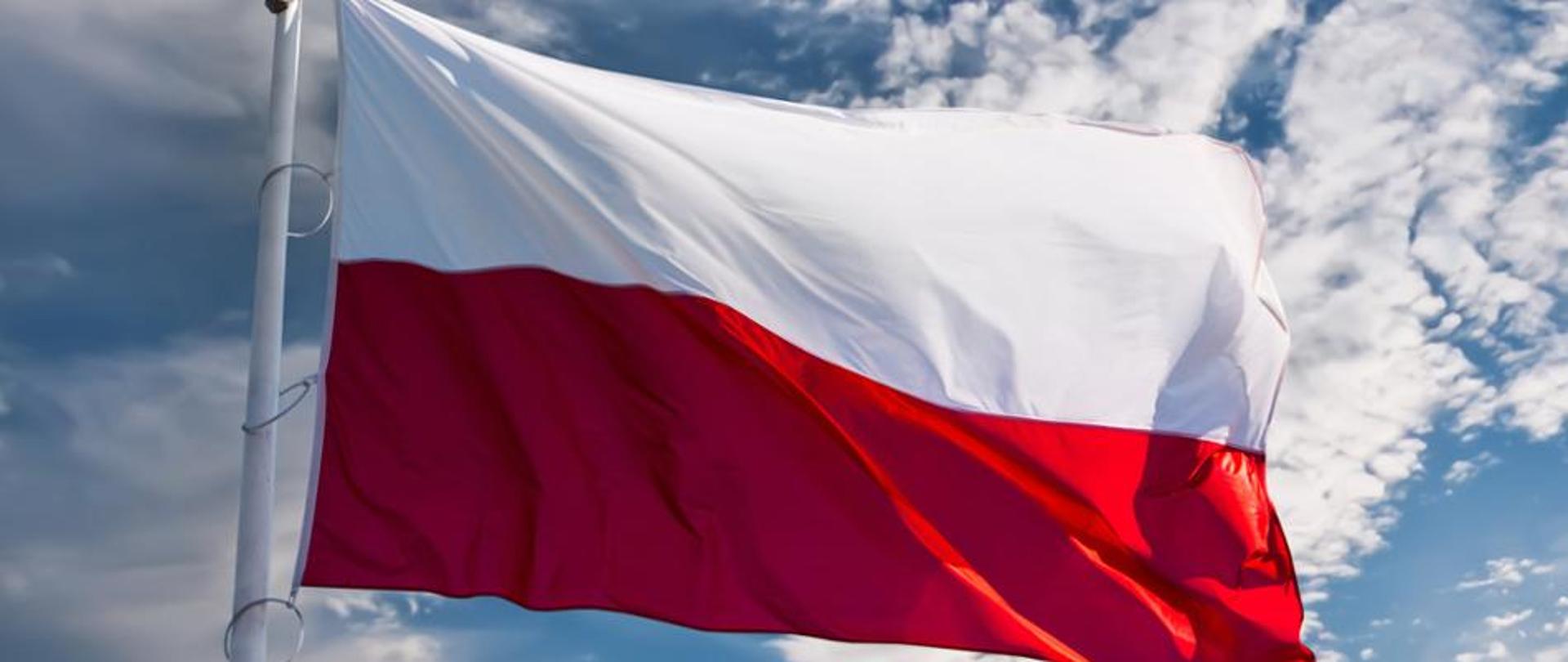 Na zdjęciu na tle błękitnego nieba flaga Rzeczypospolitej Polskiej.