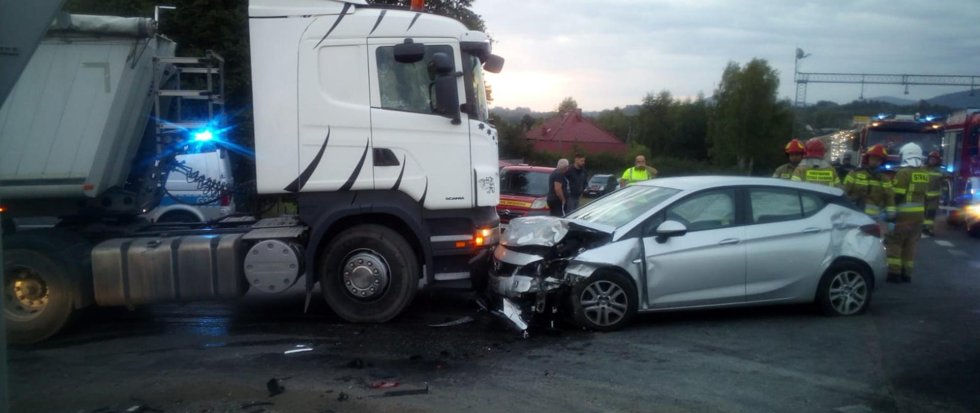 Zdjęcie przedstawia uszkodzone samochody oraz strażaków.
