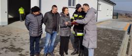 Na zdjęciu w powiatowym magazynie pomocy przed halą widoczni starosta gorlicki i zastępca kd-cy JRG PSP w Gorlicach oraz trzy osoby cywilne uzgadniają szczegóły zbiórki darów dla Ukrainy.