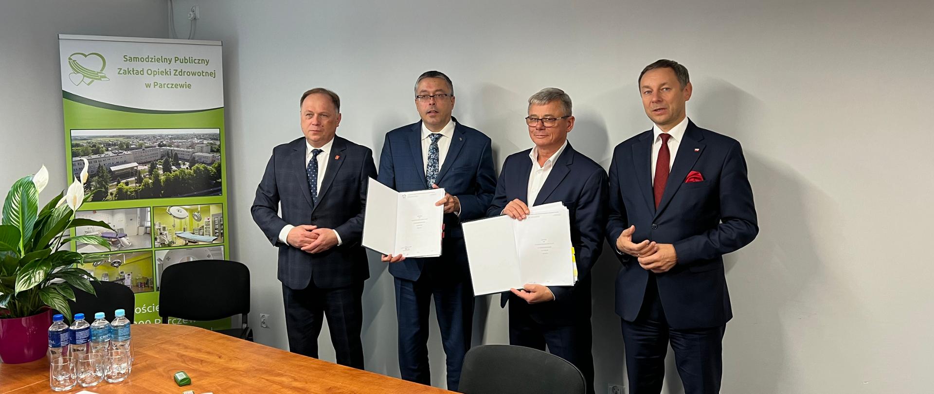 Na zdjęciu: przy ścianie, za stołem stoją od lewej, kolejno: Jerzy Szwaj, wiceprzewodniczący Rady Nadzorczej Wojewódzkiego Funduszu Ochrony Środowiska i Gospodarki Wodnej w Lublinie, Artur Michalski, wiceprezes Narodowego Funduszu Ochrony środowiska i Gospodarki Wodnej, prawej Jarosław Ostrowski, dyrektor naczelny Samodzielnego Publicznego Zakładu Opieki Zdrowotnej w Parczewie oraz Ryszard Madziar, Ministerstwo Aktywów Państwowych. Prezes Michalski i dyrektor Ostrowski trzymają w rękach podpisaną umowę.