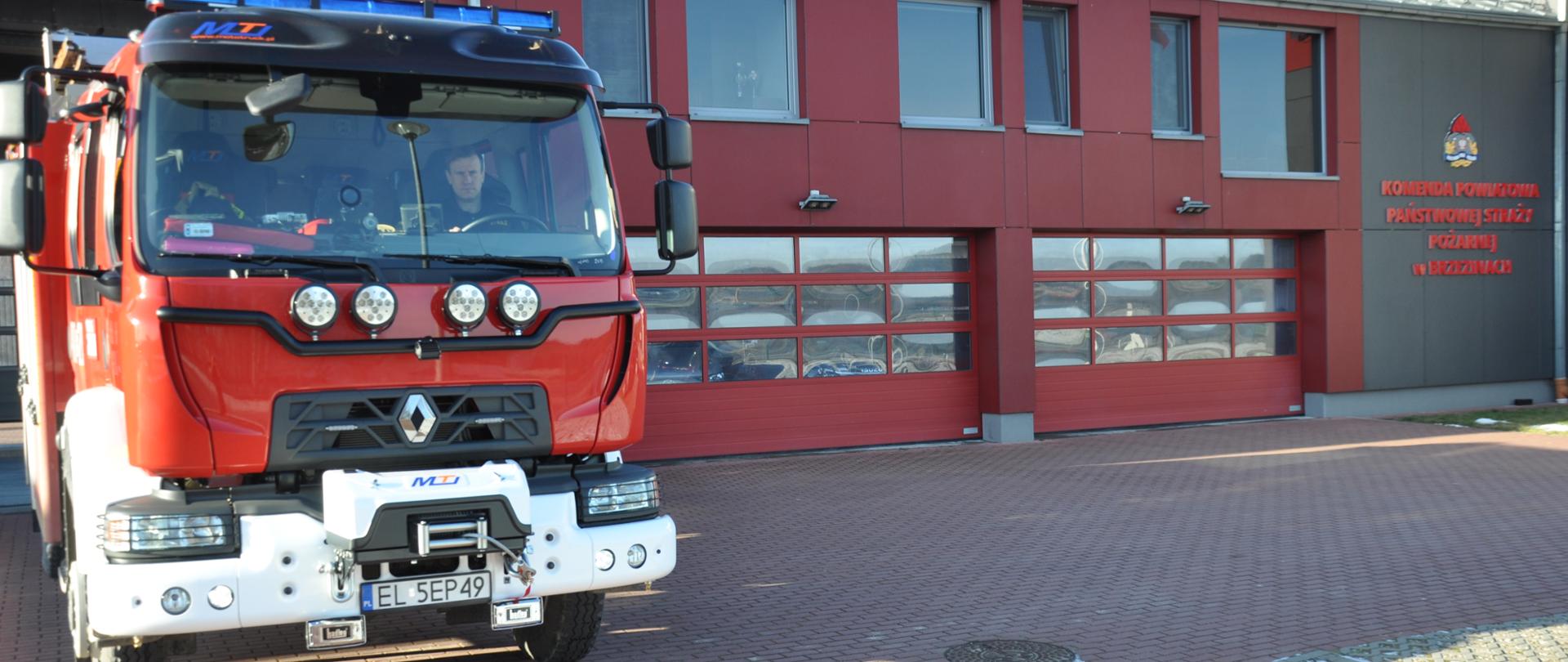 Przód nowego pojazdu marki Renault na tle garażu komendy powiatowej