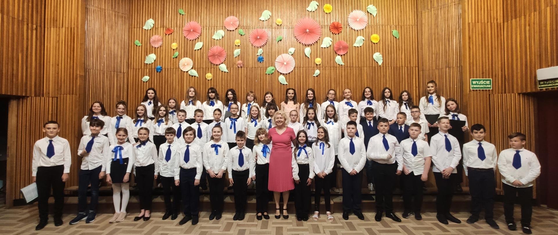 Dzieci śpiewające w chórze razem z dyrygentką na scenie ZSM w Krośnie