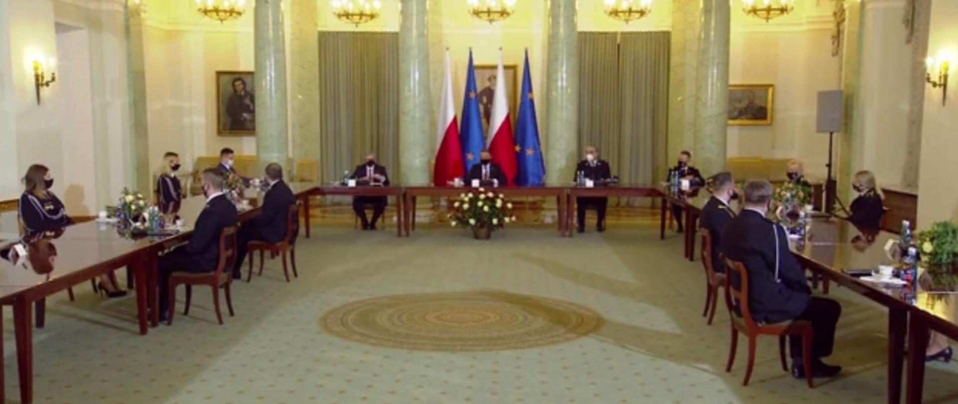 Na wprost przy stole Prezydent RP Pan Andrzej Duda po dwóch stronach stołu siedząc zaproszeni goście strażacy PSP oraz OSP