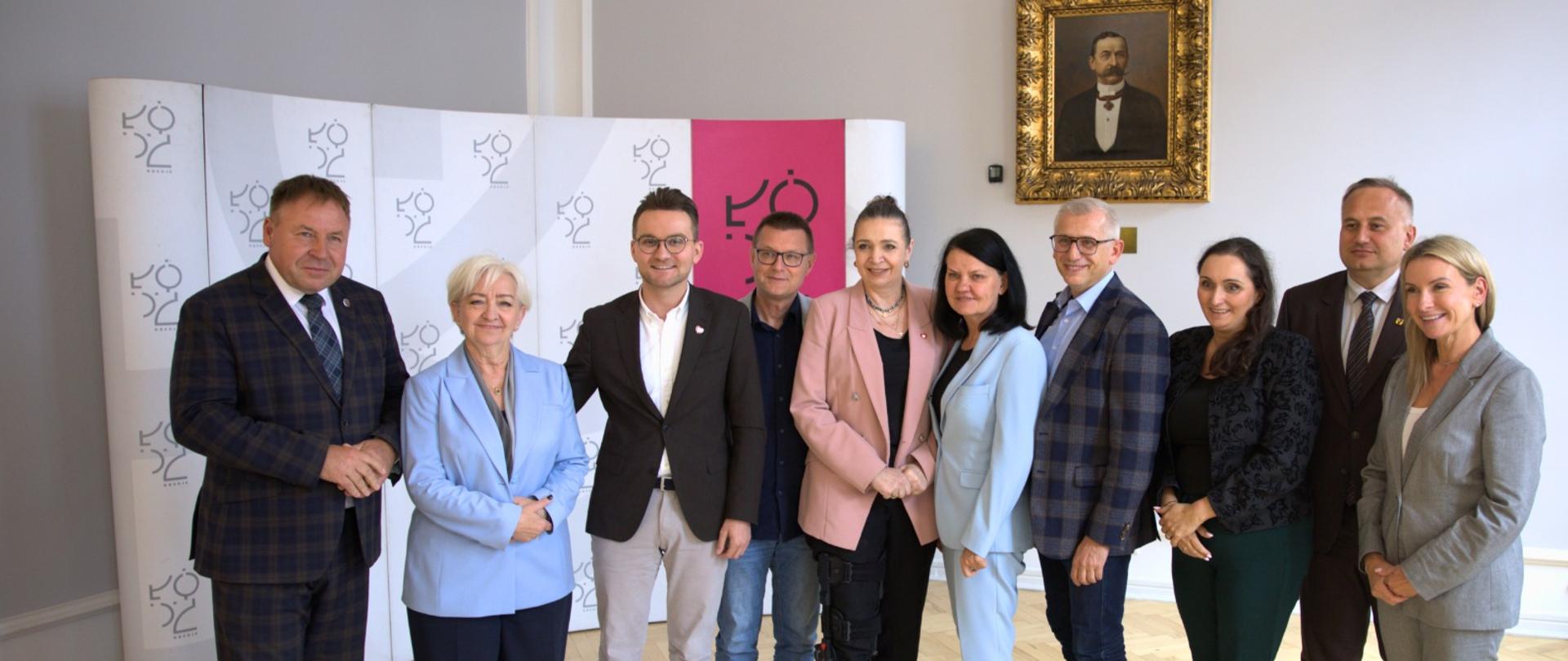 Dziesięć osób w garniturach pozuje do zdjęcia grupowego.