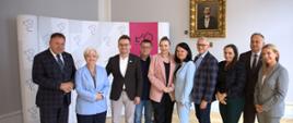 Dziesięć osób w garniturach pozuje do zdjęcia grupowego.